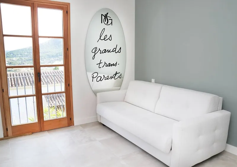 Estancia con sofá blanco, cuadro tipográfico y puerta-ventana a la terraza