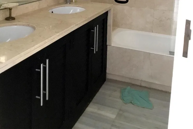 Antes: baño principal con mueble oscuro, encimera de mármol y bañera