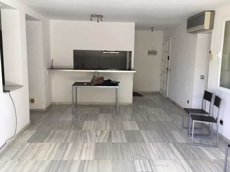 Antes: salón con suelo de mármol y la cocina al fondo