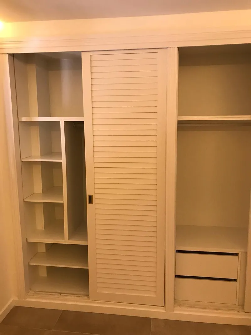 Armario empotrado con puerta de lamas y estantes