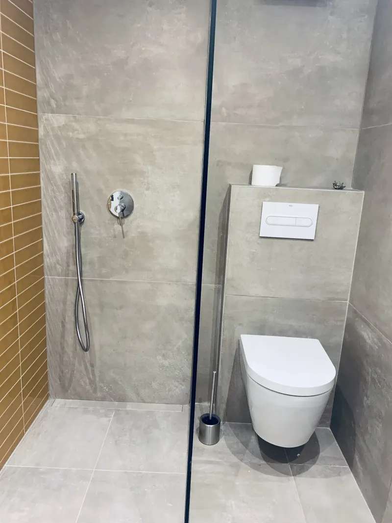 Segundo baño con ducha de azulejo mostaza e inodoro suspendido