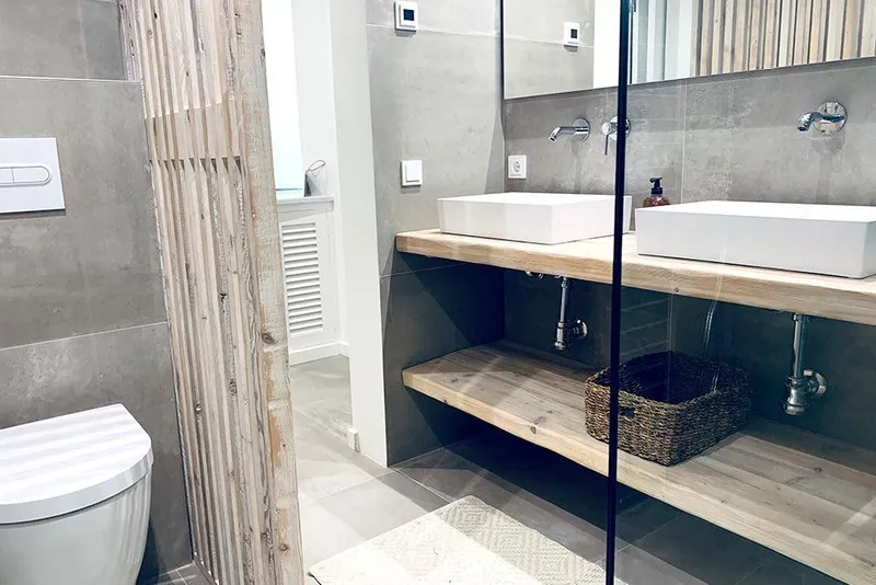 Después: baño principal con lavabos sobre encimera de madera, celosía de listones y ducha