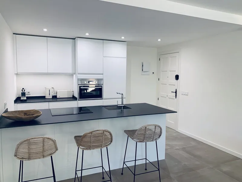 Isla de cocina con encimera de Neolith Nero y suelo de gran formato en cemento claro