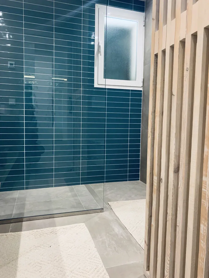 Ducha amplia con azulejo azul y celosía de madera