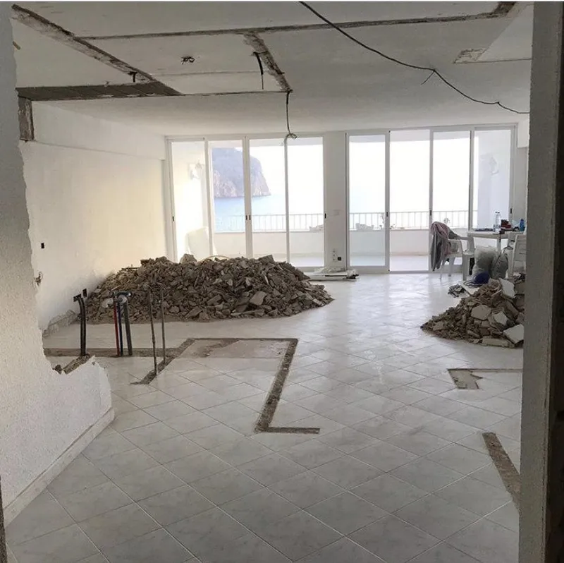 Antes: interior demolido con escombros y ventanales al fondo