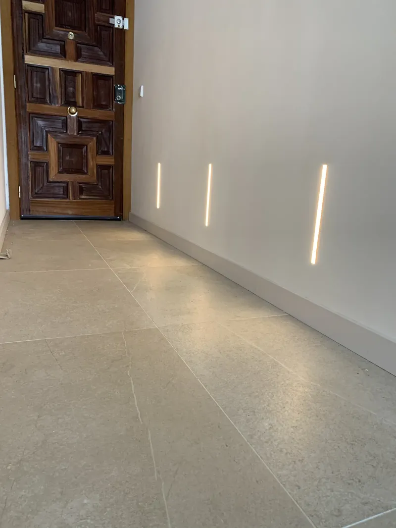 Entrada con puerta de madera tallada y líneas de luz en la pared