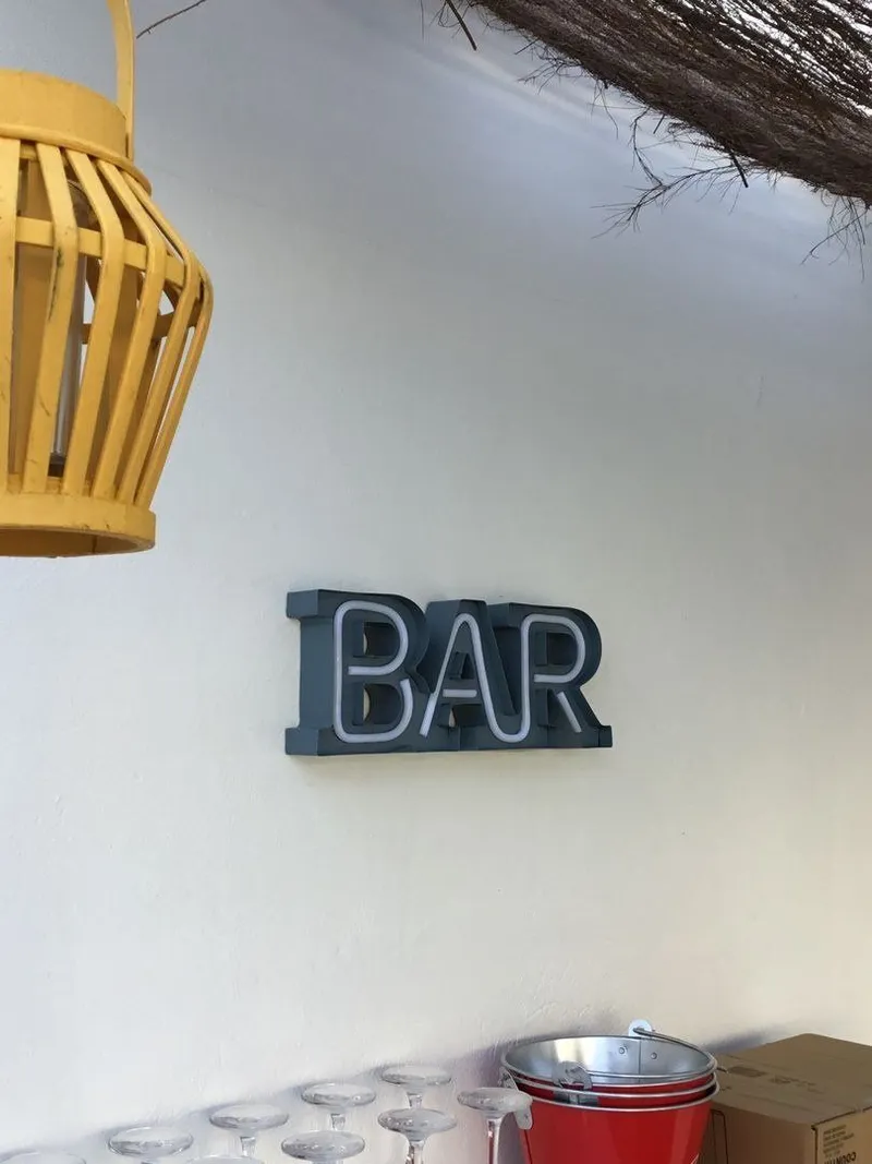 Rótulo BAR y farolillo amarillo sobre pared blanca