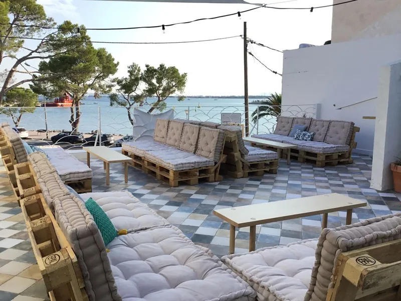 Terraza con colchonetas grises, mesas bajas de madera y suelo de baldosa azul