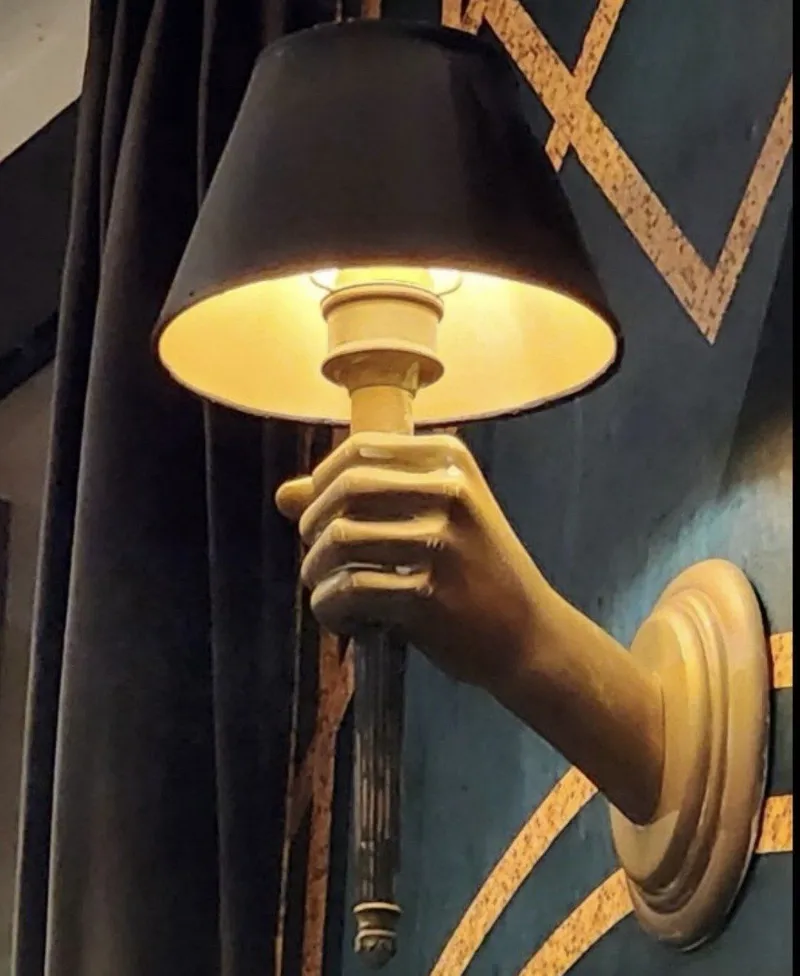 Aplique escultórico con forma de mano sosteniendo una pantalla