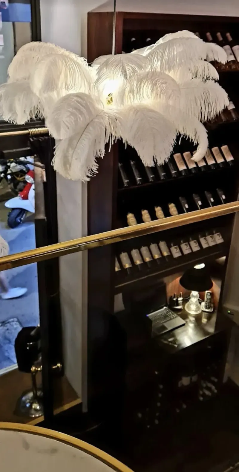 Botellero de madera oscura con plumas decorativas blancas