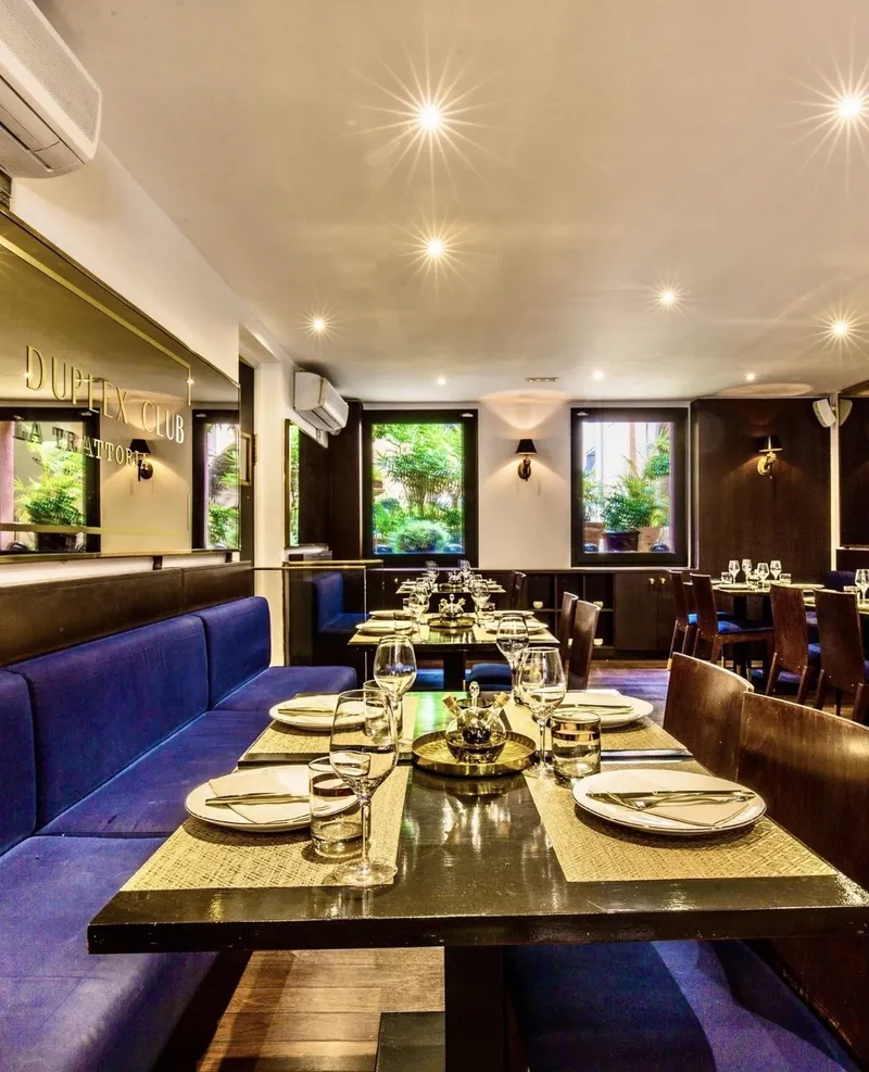Comedor con bancos de terciopelo azul, mesas preparadas y espejos