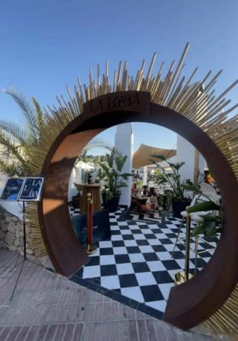Arco circular de entrada con varas de madera y suelo de damero blanco y negro