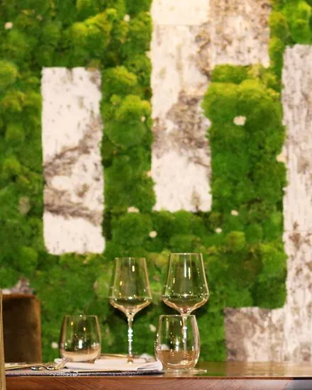 Moss and birch wall with glasses on the table at Restaurante Adrián Quetglas