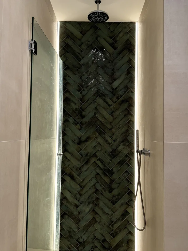 Ducha con revestimiento verde en espiga, rociador de techo y luz lateral