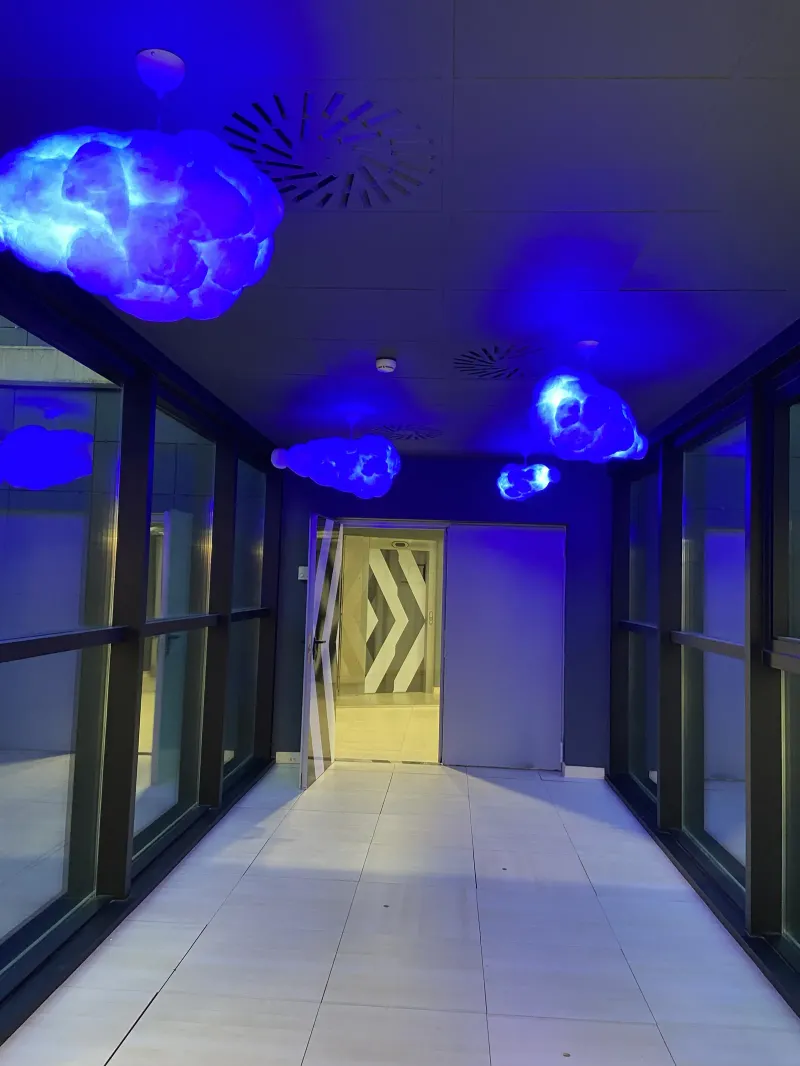 Pasarela de entrada con lámparas en forma de nube y luz azul