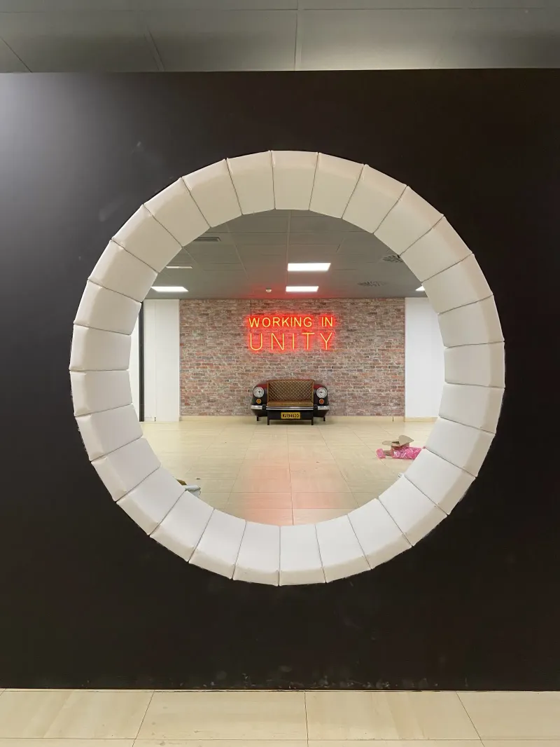 Portal circular tapizado en blanco que enmarca el neón Working in Unity