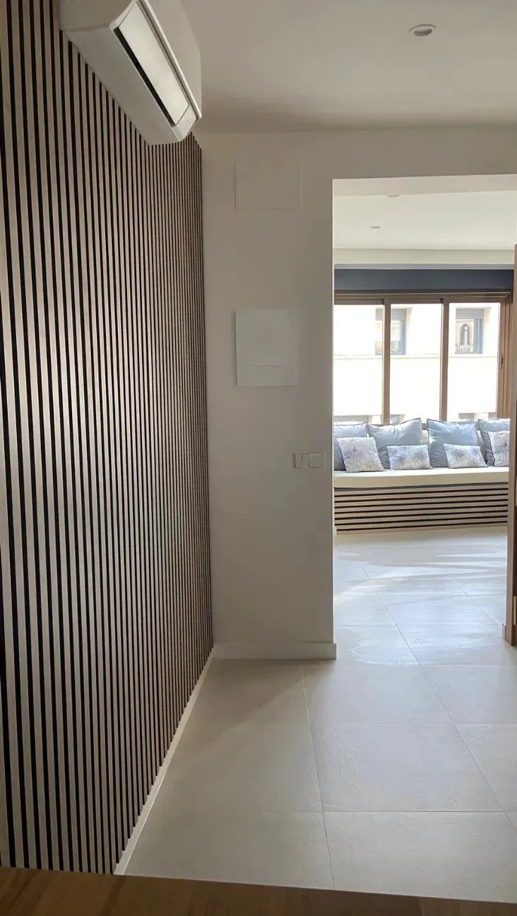 Pasillo con pared de listones de madera que conduce a un banco junto a la ventana