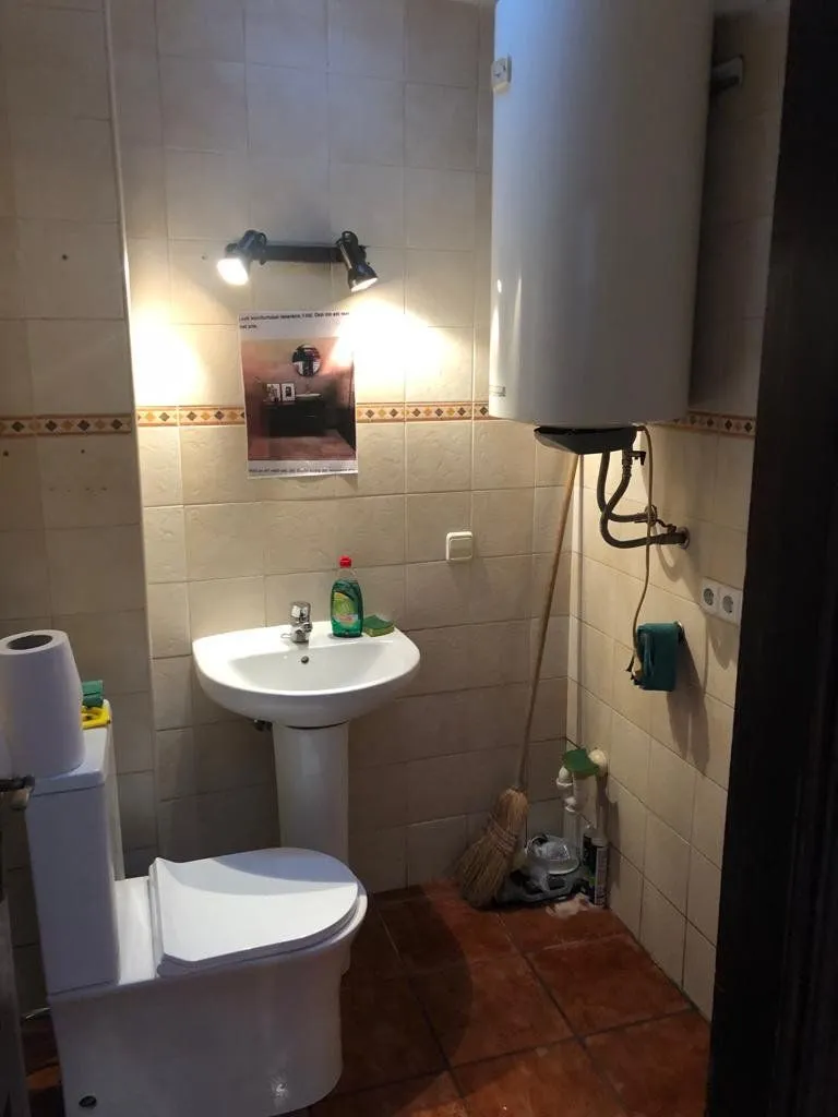 Antes: aseo con alicatado beige, lavabo de pie y suelo de terracota