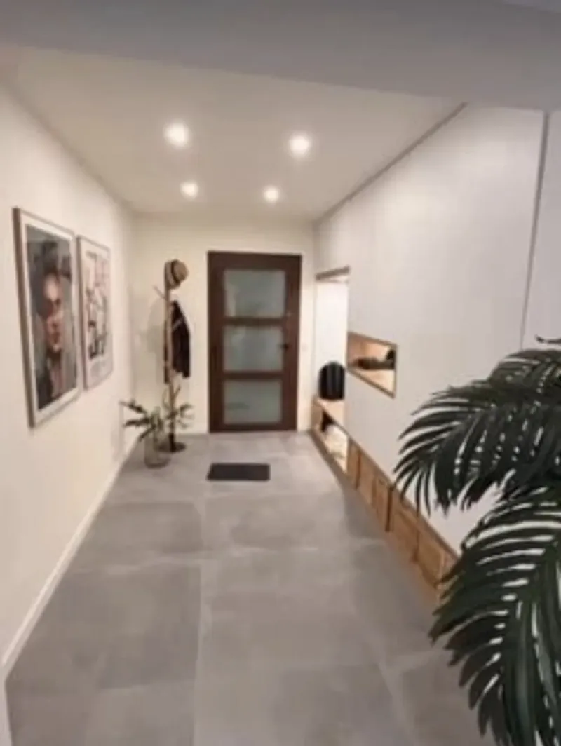 Entrada abierta con suelo gris de gran formato y banco de madera