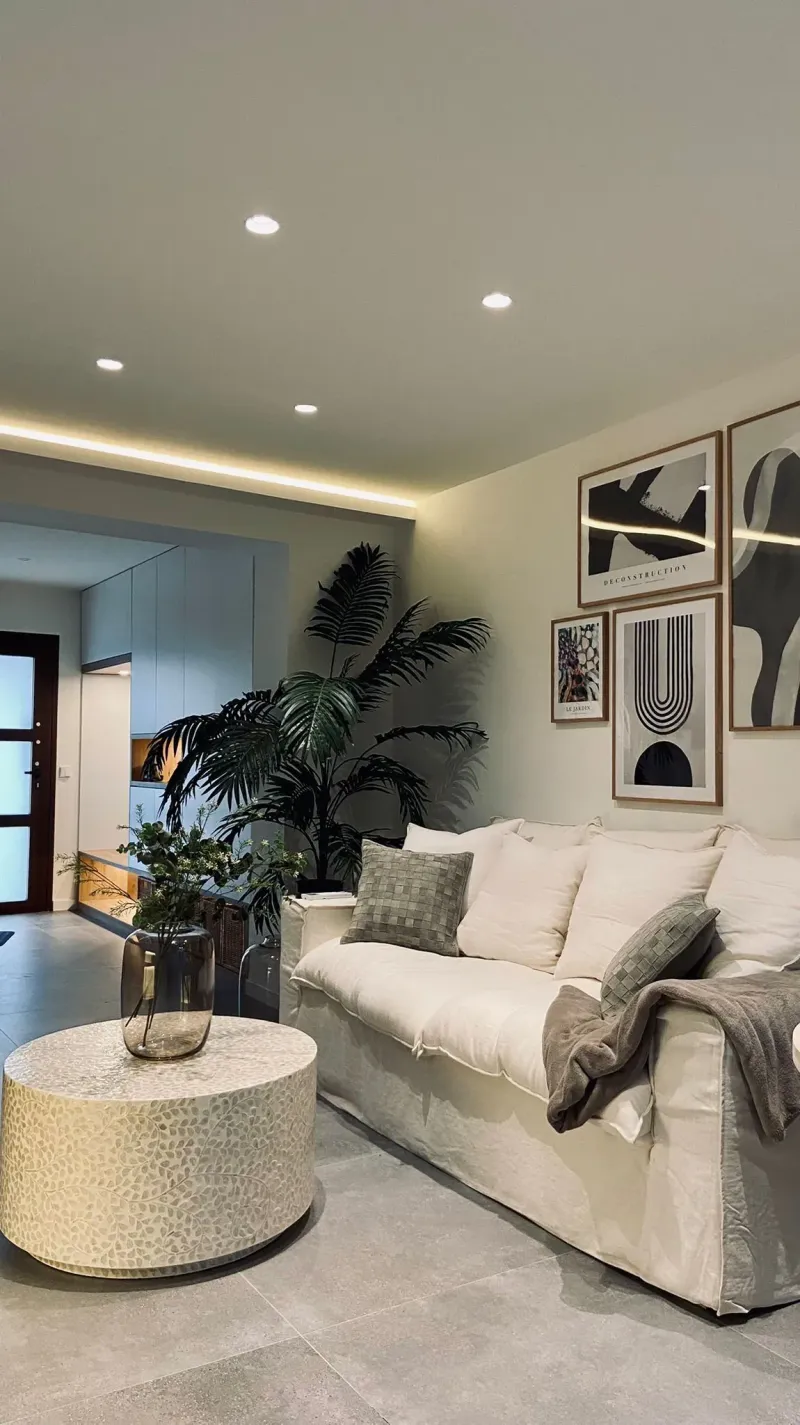 Salón con sofá claro, mesa de centro redonda y luz empotrada