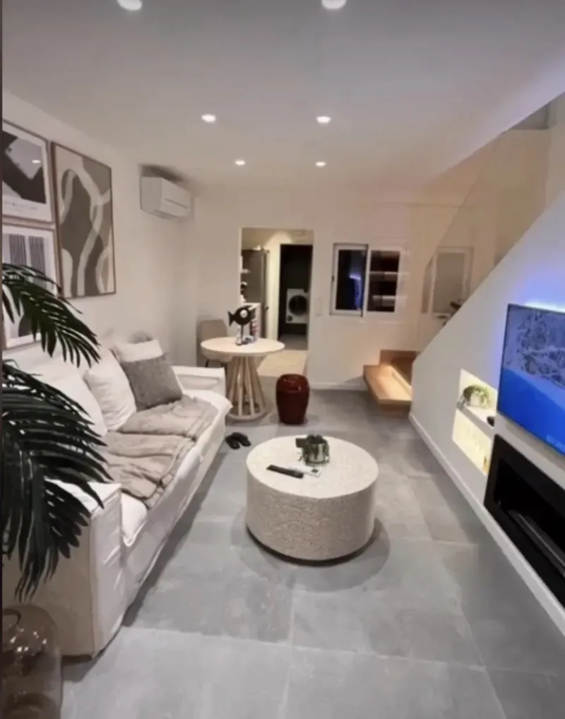 Vista del salón hacia la escalera, con chimenea empotrada y suelo continuo