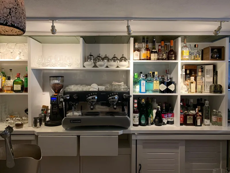 Antes: botellero y estanterías lacadas en blanco tras la barra