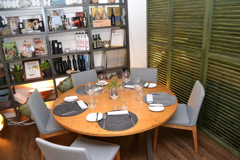 Antes: esquina de la sala con mesa redonda, estantería de madera y persianas mallorquinas