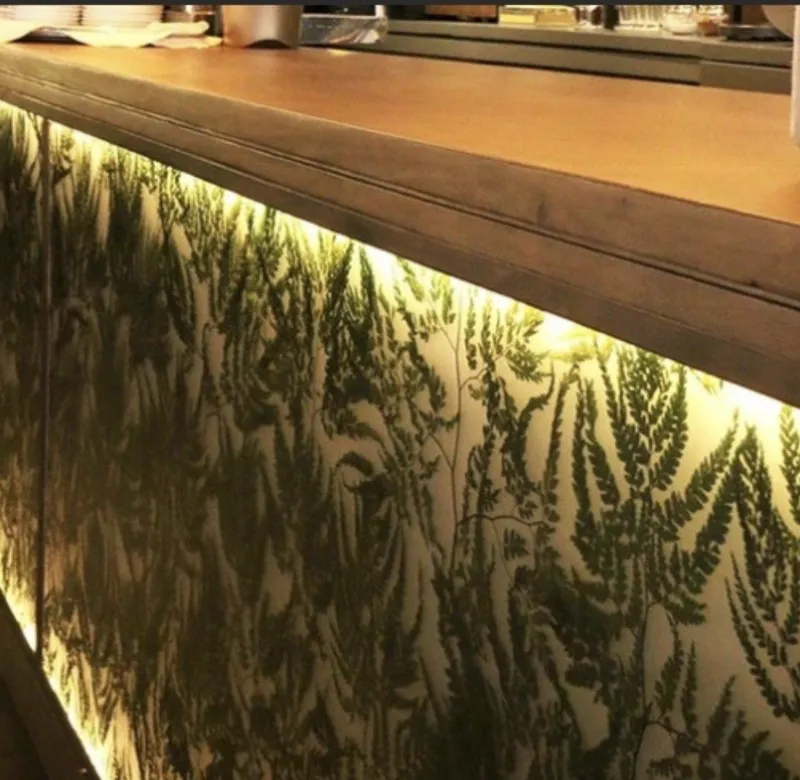 Después: frente de barra con helechos retroiluminados y encimera de madera