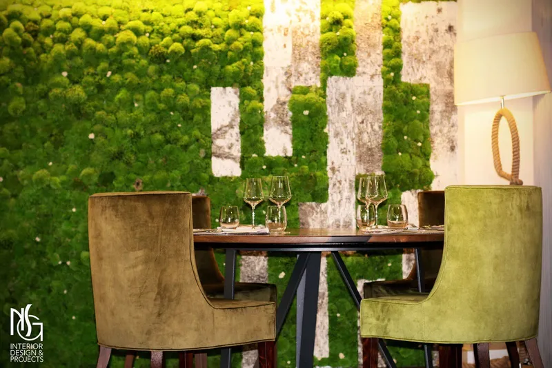 Muro de musgo estabilizado y abedul con butacas de terciopelo verde y mesa preparada