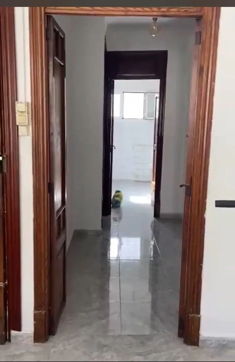 Antes: pasillo con puertas de madera oscura y suelo de terrazo