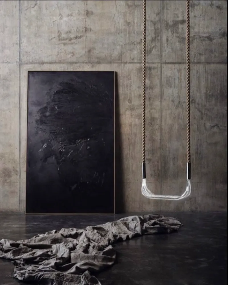 Columpio Light Swing de Saas Instruments colgado en un interior de hormigón y obra de arte negra