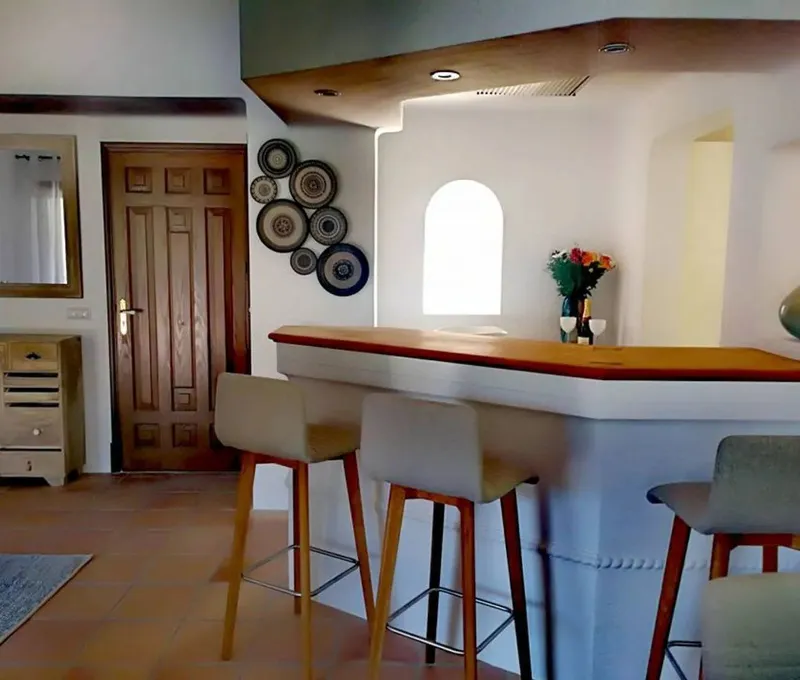 Barra de cocina con taburetes de madera y platos decorativos en la pared