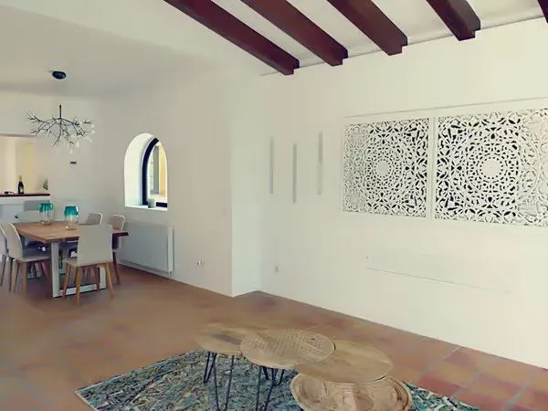 Después: salón comedor decorado, con lámpara de diseño y la pared de paneles tallados