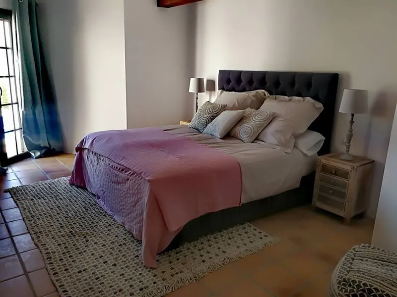 Después: dormitorio principal con cama gris oscuro y mesitas de madera
