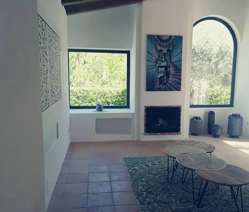 Salón con chimenea, ventana en arco, alfombra de colores y mesas de centro de madera
