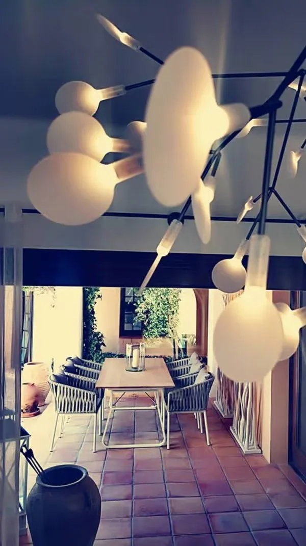 Después: terraza cubierta con mesa larga de roble, sillas trenzadas y lámpara colgante